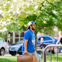 An Alumnus carrying a student's suitcase.